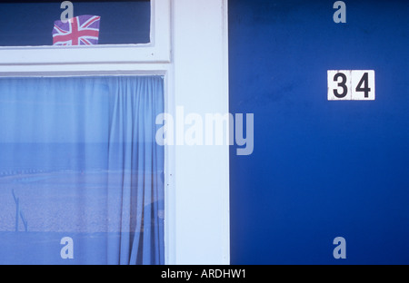 Tür Haus oder Chalet mit Nummer 34 neben Netto verhangenen Fenster mit Strand Reflexion und winzige Union Jack-Flagge Stockfoto