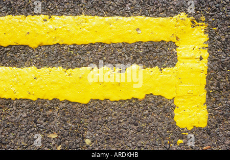 Detail aus direkt oberhalb der neu lackiert doppelte gelbe Linien mit Ende Bar auf schwarzem Asphalt Fahrbahn Stockfoto