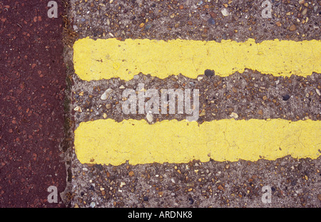 Detail aus direkt oberhalb von abgenutzten gelbe Doppellinien auf konkrete Fahrbahn und am Ende sie rosa Asphalt treffen Stockfoto