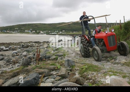 zwei junge Männer auf einem roten Traktor auf Inishkeel Island, County Donegal, Irland Stockfoto