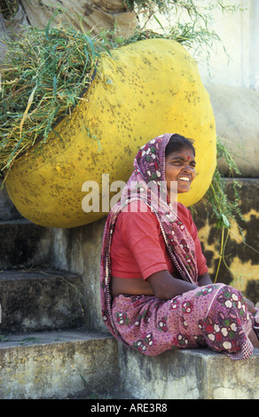 Lächelnde Frau Porter ruht ihr riesige Ladung Rasen Futter bei Sonagiri India Stockfoto