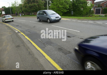 Autos fahren durch ein Schlagloch auf der Straße UK Stockfoto