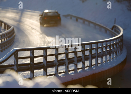 Metallische verschneite Straße Brücke Geländer und Auto fahren auf der Straße im Winter, Finnland Stockfoto