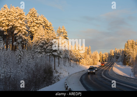 Autos, die an der eisigen Autobahn bei Abendlicht im Winter fahren, Finnland Stockfoto