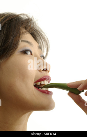 Kopfschuss hübsche Frau mit roten Lippen halten heiße grüne Chilischote Stockfoto