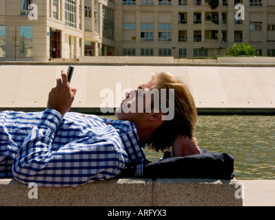 Eine Nahaufnahme von einem kaukasischen Jungunternehmer mit Blackberry auf einer Bank in einem Geschäftsviertel liegend Stockfoto