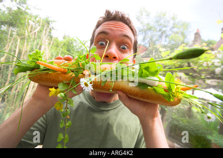 Ein zwanzig-etwas weißer Mann greift eine enorme vegetarische Mahlzeit Stockfoto