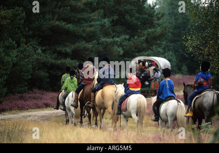 Gruppe von Mädchen und ihre Pferde Reiten in der Heide zusammen mit einem Wohnwagen Stockfoto