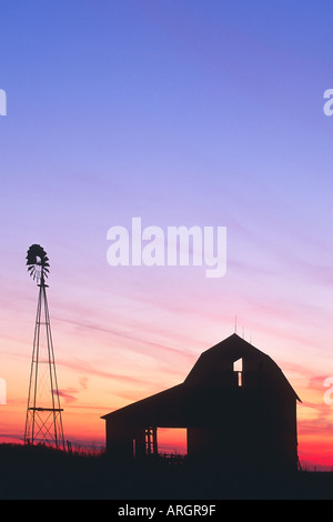 Ein schöner Sonnenuntergang mit einer Windmühle und Scheune Silhouette gegen den Abendhimmel im ländlichen Indiana USA Stockfoto