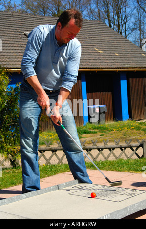 Junger Mann, des erste Schlag junge Mannes auf eine Minigolfanlage Stockfoto