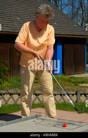 Vor dem Streik ältere Dame Golfen auf einer Minigolfanlage Stockfoto