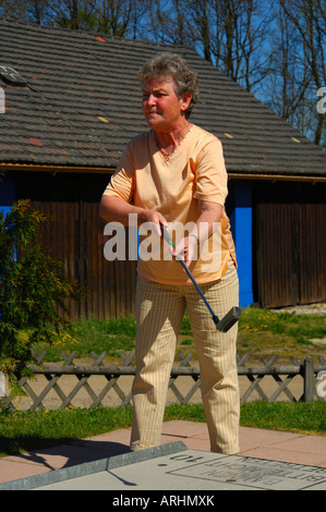 Ältere Dame, die auf ein Mini-Golfplatz Golfen Stockfoto