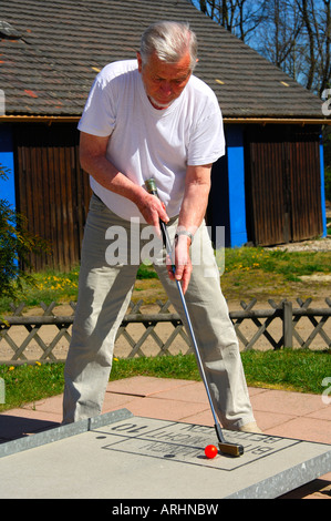 Älterer Mann wird auf ein Mini-Golfplatz Golfen. Stockfoto