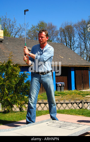 Junger Mann, des erste Schlag junge Mannes auf eine Minigolfanlage Stockfoto