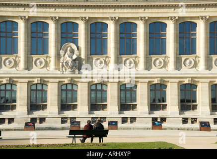 Bild von ein paar sitzt auf einer Parkbank zusammen vor der Grande Galerie d Evolution in Paris Frankreich Stockfoto
