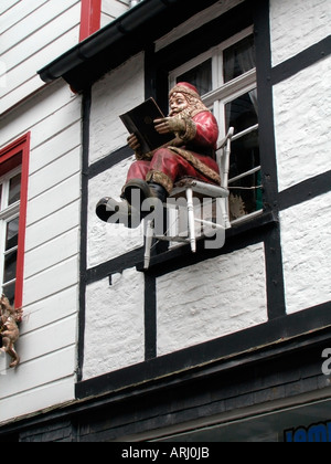 Santa Claus hängen Fassade ein halb Fachwerkhaus sitzen auf einem Stuhl, ein Buch zu lesen Stockfoto