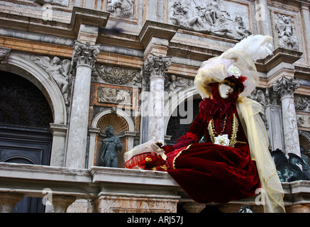 Person saß auf einer Mauer, gekleidet in Maske und Kostüm im Karneval von Venedig-Venetien-Italien Stockfoto