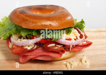 Coseup eines gefüllten Bagel-Sandwiches auf weißem Hintergrund mit einem Salat auf einem Holzbrett über dem Kopf isolierter Ausschnitt, der horizontal in den USA hochauflösend ausgeschnitten wird Stockfoto