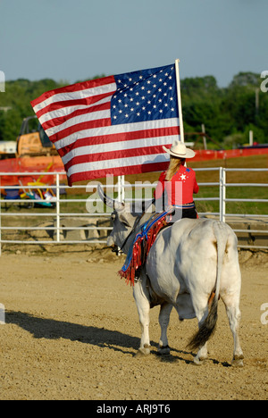 Weibliche Cowgirl reitet einen Brama Stier die Flagge in der Zeremonie vor einem rodeo Stockfoto