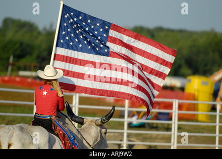 Weibliche Cowgirl reitet einen Brama Stier die Flagge in der Zeremonie vor einem rodeo Stockfoto