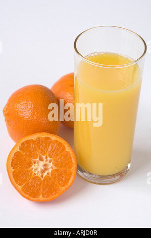 Frisch gepressten Bio-Orangensaft in ein Glas umgeben von geschnittenen & ganze Orangen gegen weiß Stockfoto