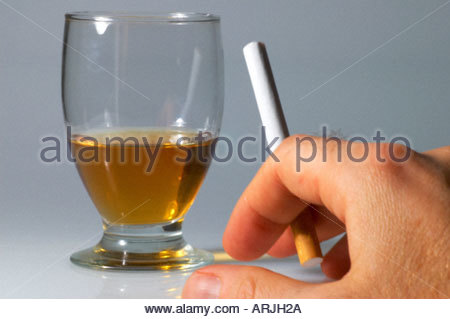 Ein Mann raucht eine Zigarette und ein Glas Whisky zu erreichen Stockfoto