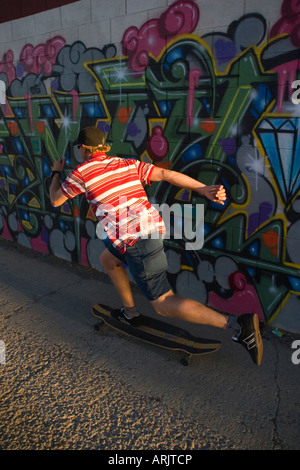 Rückansicht eines Mannes skaten entlang ein Graffiti bedeckt Wand, Reno, Nevada, USA Stockfoto