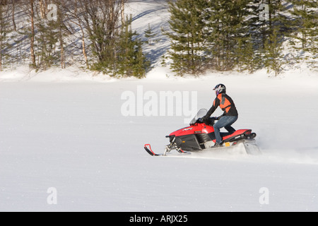 Junger Mann fahren mit Motorschlitten auf ununterbrochene Schnee im Winter, Finnland Stockfoto