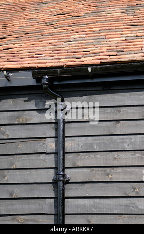 Neue schwarze Gusseisen Dachrinnen und Fallrohr installiert auf einer schwarzen weatherboarded Scheune Stockfoto