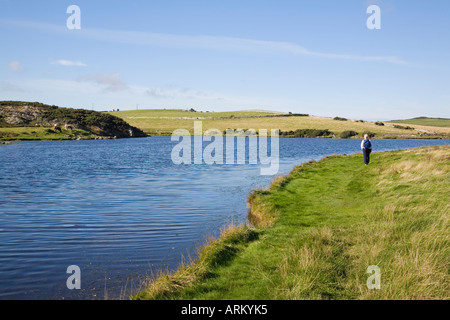 CEMLYN BAY Lagune mit Walker auf Isle of Anglesey Coastal Path entlang Schindel bar Anglesey North Wales Stockfoto