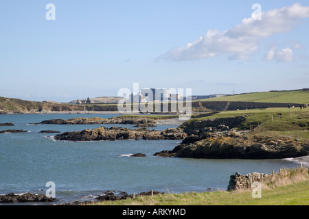 ZERKLÜFTETE Küste mit Kernkraftwerk Wylfa über Henne Borth Bucht von Isle of Anglesey Coastal Path. Cemlyn Anglesey Wales Stockfoto
