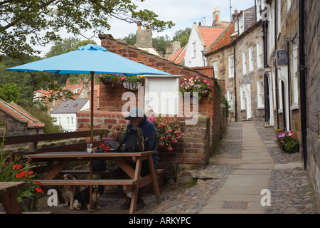 Reihenhäuser in "Chapel Street" mit blauen Sonnenschirm Regenschirm von Café in Old Bay Teil "Robin Hoods Bay" Yorkshire England Stockfoto