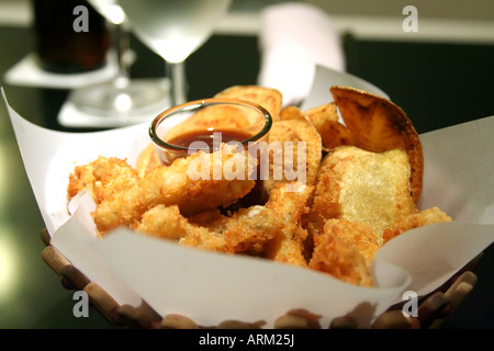 Snack-Korb mit gebratenen Calamari und Kartoffel-Chips-Restaurant-Einstellung Stockfoto