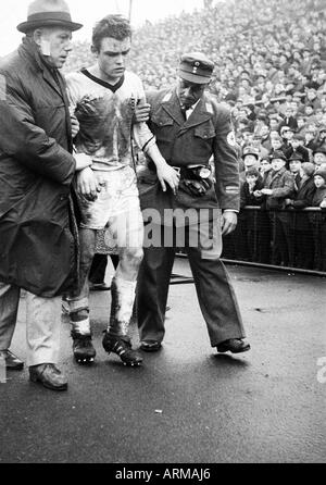 Fußball, Regionalliga West 1964/1965, Borussia Mönchengladbach gegen Preussen Münster 0:0, Boekelberg Stadion in Mönchengladbach, verletzte Fußballspieler, Herbert Laumen (MG) ist unter der Leitung von der Tonhöhe von Mannschaftsarzt Dr. Alfred Gerhards (links) und eine Amb Stockfoto