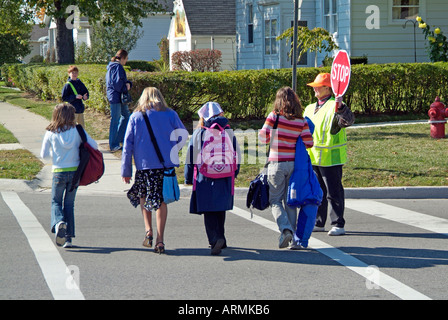 Grundschule Crossing Guard bietet Sicherheit für Kinder überqueren von verkehrsreichen Straßen Straßen Autobahnen beim Heimweg von der Schule Stockfoto