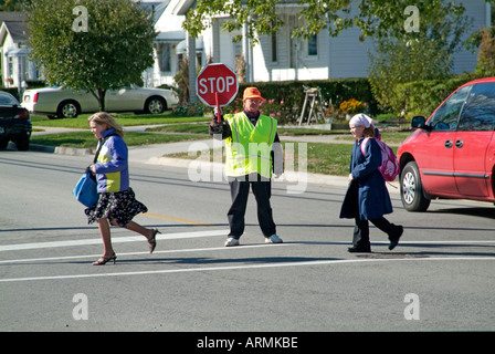 Grundschule Crossing Guard bietet Sicherheit für Kinder überqueren von verkehrsreichen Straßen Straßen Autobahnen beim Heimweg von der Schule Stockfoto