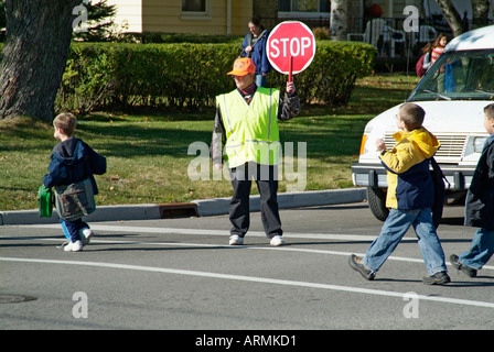 Grundschule Crossing Guard bietet Sicherheit für Kinder überqueren von verkehrsreichen Straßen Straßen Autobahnen beim Heimweg von der Schule Stockfoto