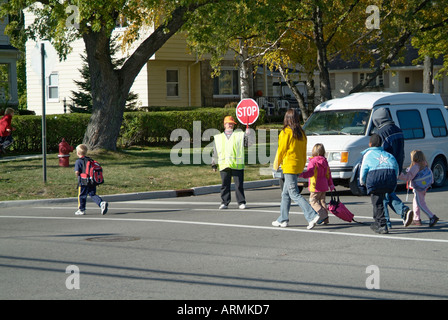 Grundschule Crossing Guard bietet Sicherheit für Kinder überqueren von verkehrsreichen Straßen Straßen Autobahnen beim Heimweg von der Schule Stockfoto