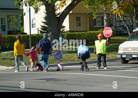 Grundschule Crossing Guard bietet Sicherheit für Kinder überqueren von verkehrsreichen Straßen Straßen Autobahnen beim Heimweg von der Schule Stockfoto