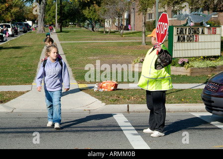 Grundschule Crossing Guard bietet Sicherheit für Kinder überqueren von verkehrsreichen Straßen Straßen Autobahnen beim Heimweg von der Schule Stockfoto