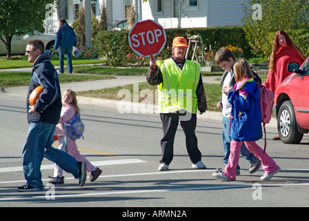 Grundschule Crossing Guard bietet Sicherheit für Kinder überqueren von verkehrsreichen Straßen Straßen Autobahnen beim Heimweg von der Schule Stockfoto