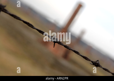 Elektrozaun Stacheldraht mit Hütte Schornsteine hinter Auschwitz Birkenhau Stockfoto