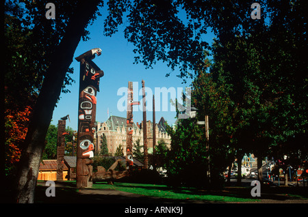 Totempfähle auf dem Gelände der British Columbian Royal Museum mit dem Empress Hotel darüber hinaus, Victoria, Vancouver Island, Brit Stockfoto