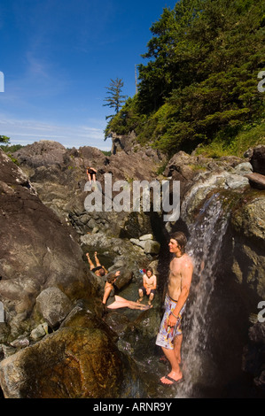 Hot Springs Cove mit jungen Mann unter warmen Wasserfall, Vancouver Island, British Columbia, Kanada. Stockfoto