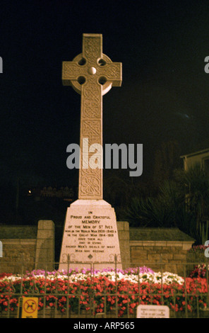 Keltisches Kreuz zum Gedenken an die Männer der Stadt, die in den beiden Weltkriegen starben, mit Blumen vor der Tür in der Nacht. St Ives, Cornwall, Großbritannien. Stockfoto