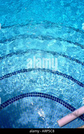 Abstrakt von Schwimmbad mit dunkelblauen Fliesen Markierung Rand der Stufen und Sonnenlicht spielen auf der Oberfläche von hellblauem Wasser. La Manga, Murcia, Spanien. Stockfoto
