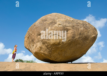 Ein Tourist steht neben Krishna s Butterball in Mamallapuram in Tamil Nadu, Indien Stockfoto