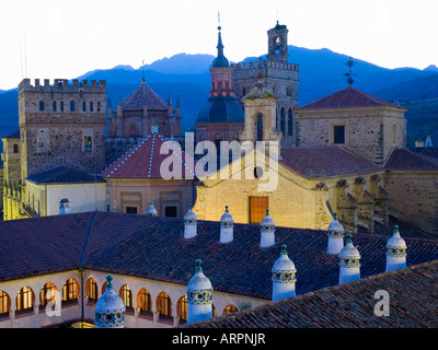 Guadalupe, Extremadura, Spanien. Die Real Monasterio de Santa María de Guadalupe in der Abenddämmerung, Dach des Parador im Vordergrund. Stockfoto