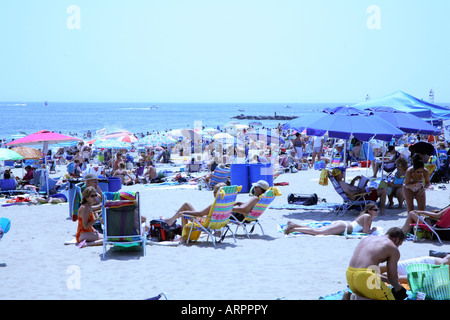 Masse von Menschen mit bunten Sonnenschirmen, Stühlen und Handtücher am Sandstrand an der Küste von New Jersey. Stockfoto