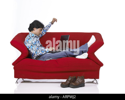 VDA200162 südasiatischen indischer Mann auf Sofa auf Laptop trägt Jeans und Hemd Herr 701 Stockfoto